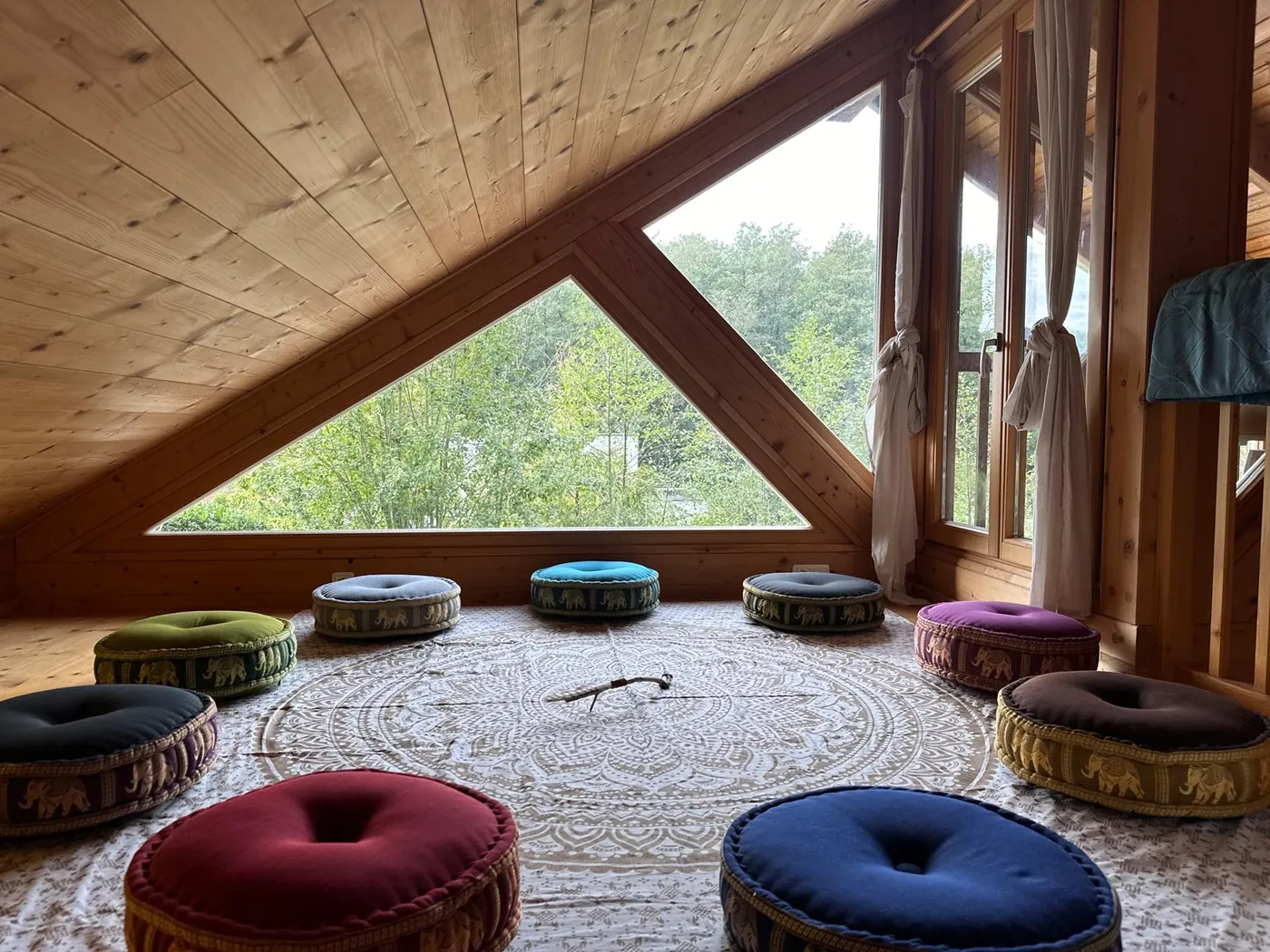 Meditationsraum mit Sitzkissen im Kreis unter dem Dreiecksfenster